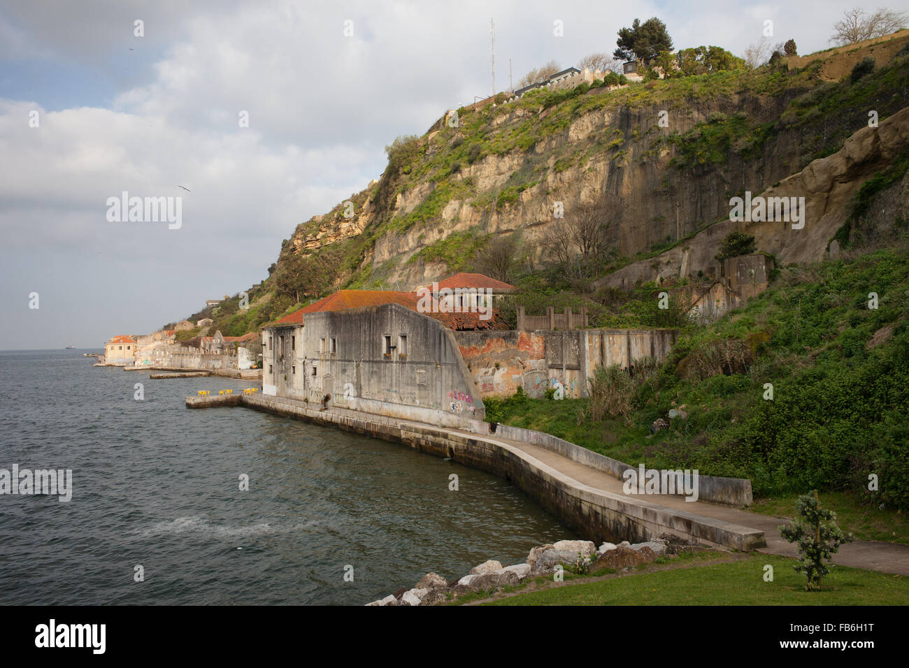 Portugal, city of Almada, old quay with mostly abandoned buildings and  cliff by the Tagus river Stock Photo - Alamy