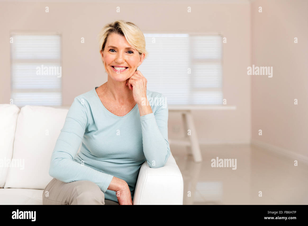 portrait of happy middle aged woman sitting on sofa Stock Photo - Alamy
