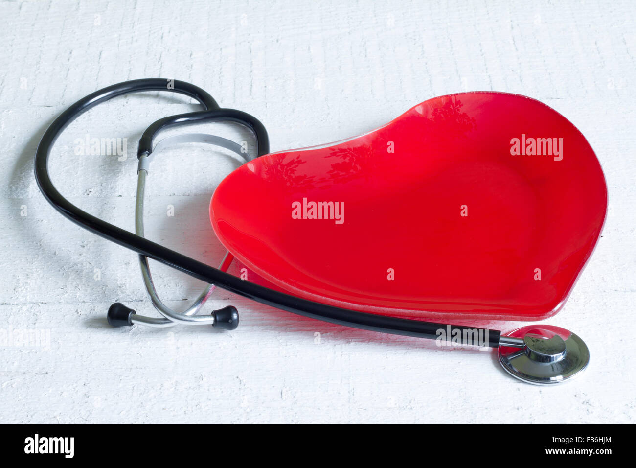 Stethoscope and a red heart plate diet concept on white boards Stock Photo