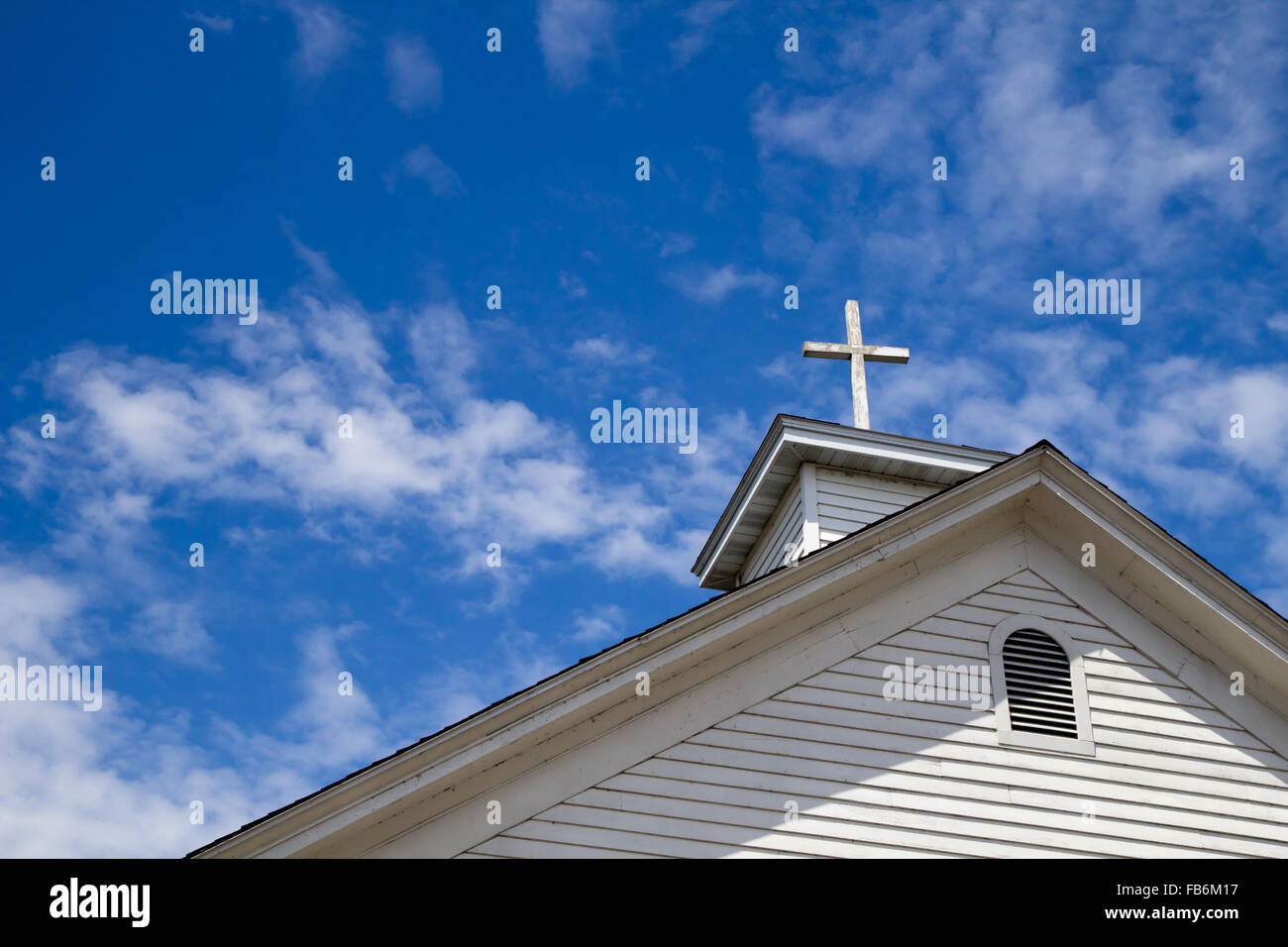 Christian Wooden Cross Background With Copy Space. Wooden cross and  steeple with a sunny blue sky and copy space. Stock Photo
