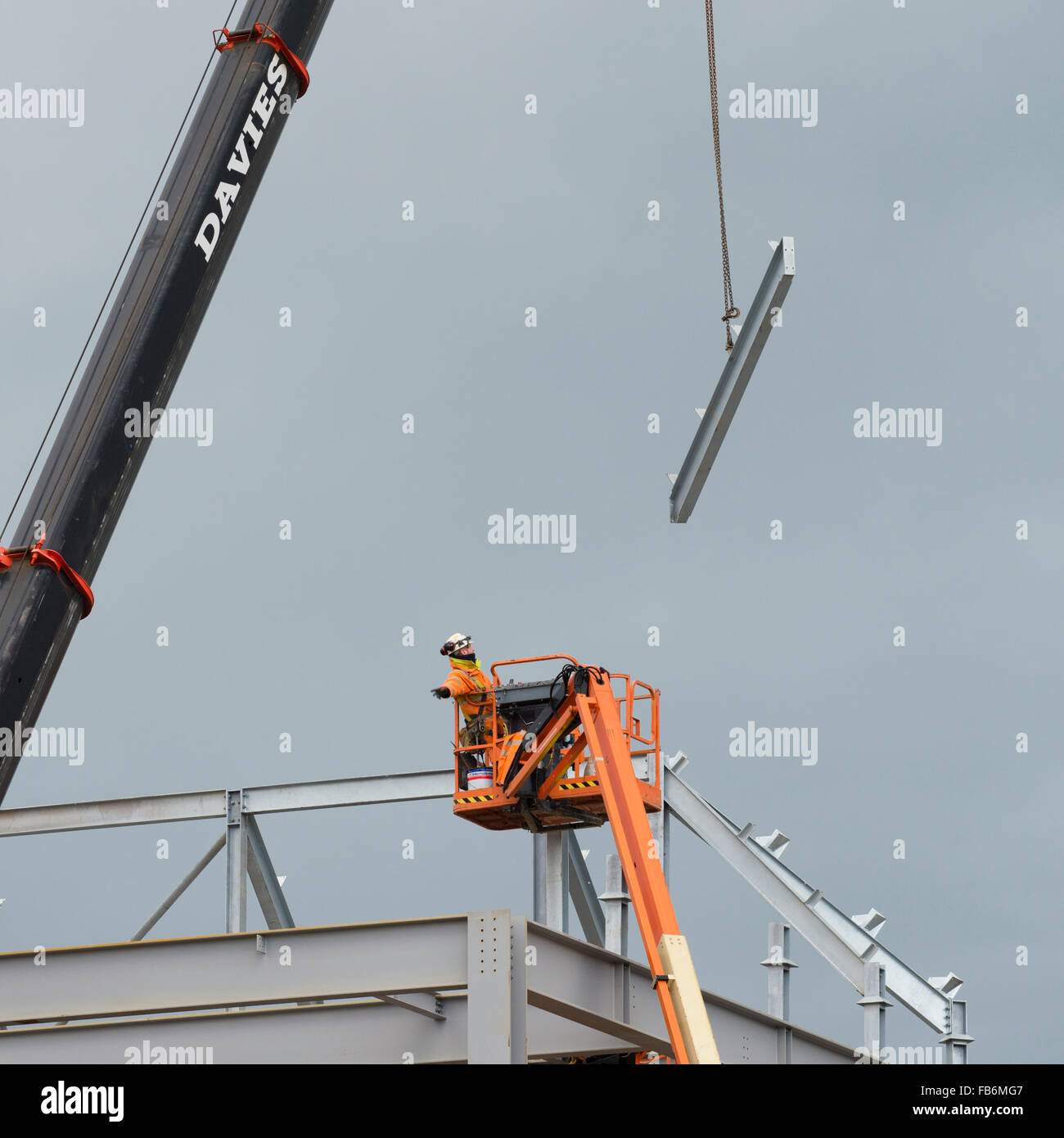 Construction work in the UK : Men working at height on elevated 'cherry picker' platforms,  bolting together the steel frame of a new development for Tesco supermarket and Marks & Spencer store  on a building site in Aberystwyth, Wales UK Stock Photo