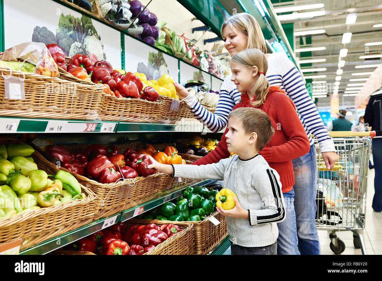 Mother and children with bell pepper in vegetables department in the supermarket Stock Photo