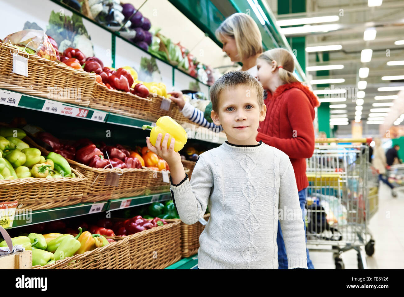 Boy holds yellow bell pepper in supermarket Stock Photo