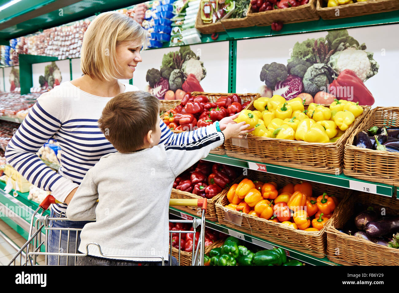 Mother and child with bell pepper in vegetables department in the supermarket Stock Photo
