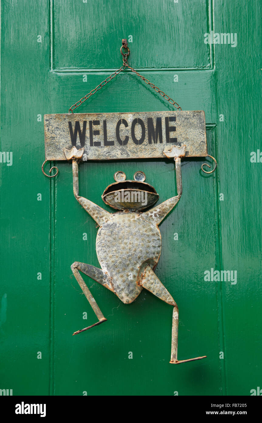 sign on a green front door, with a comical frog hanging from it