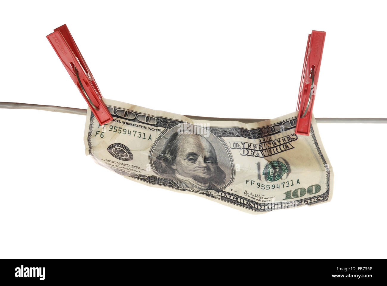 the front of the crumpled 100 dollar bill hanging on a clothesline on a white background. Stock Photo
