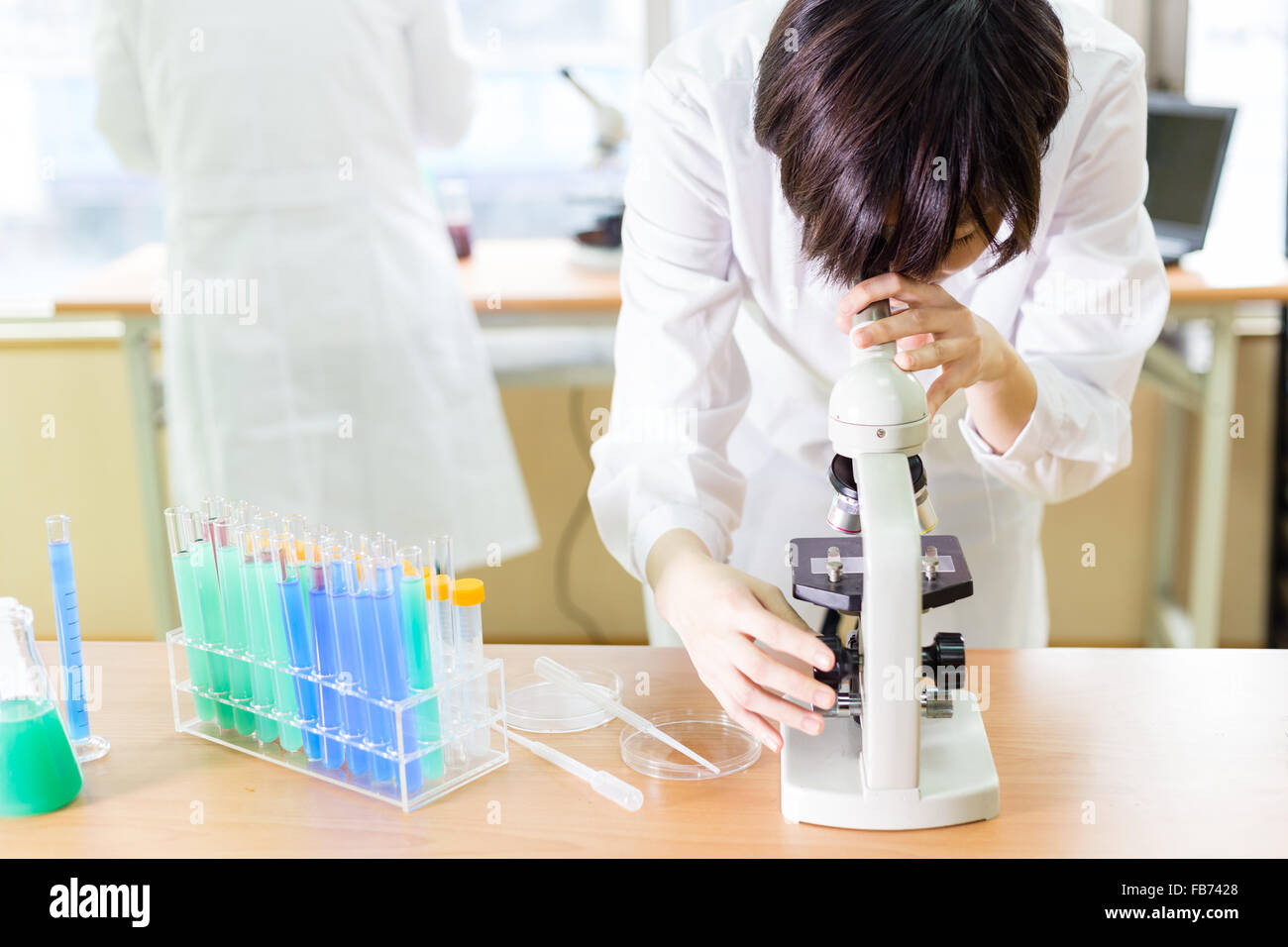 Female Chinese scientist looking into a microscope Stock Photo