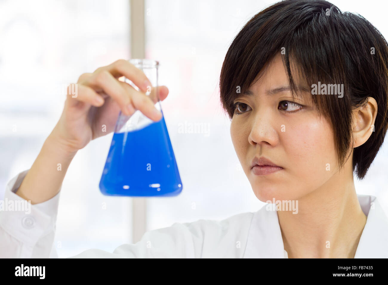 Female Chinese scientist looking at erlenmeyer flask Stock Photo