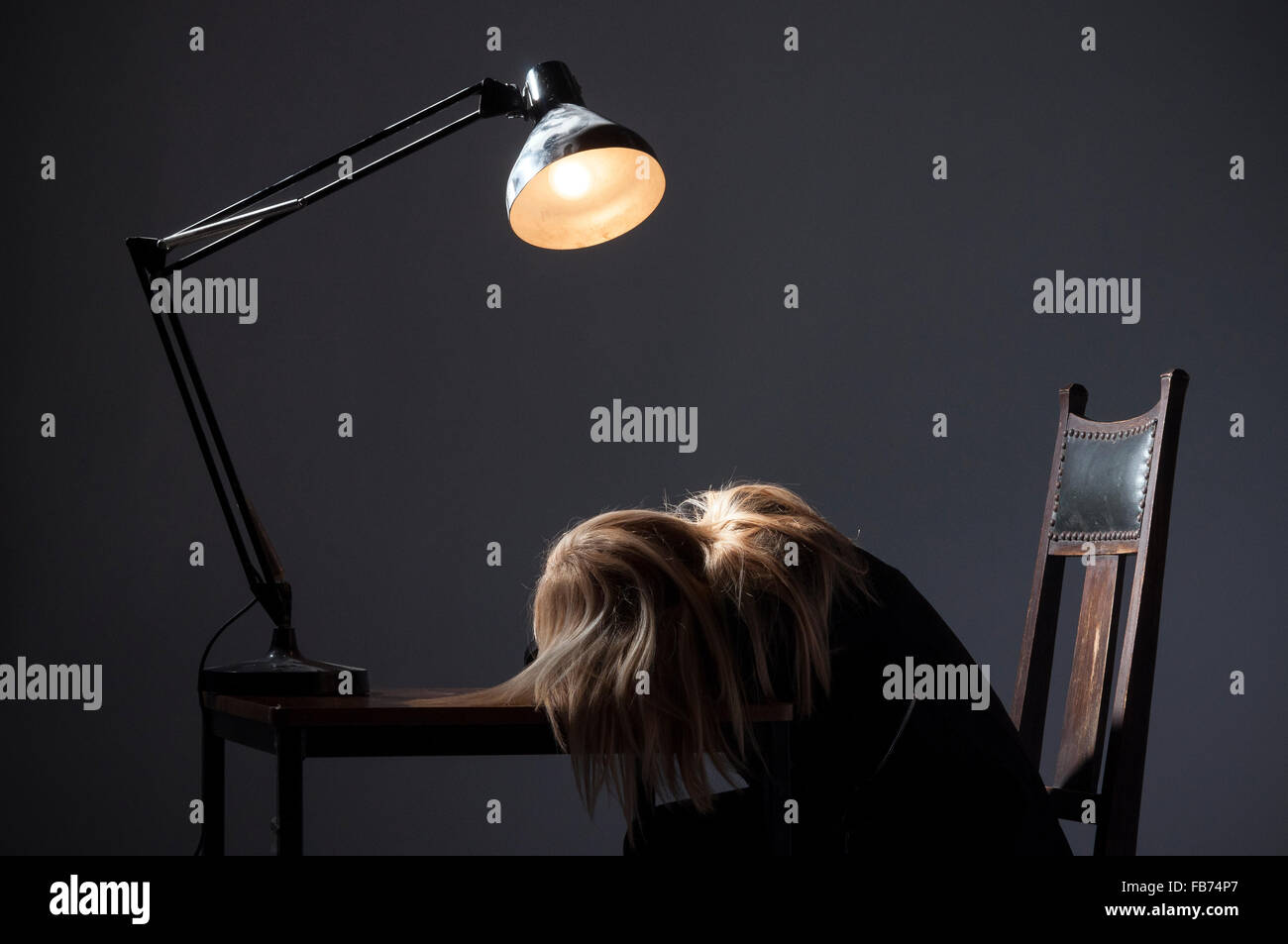 Blonde lady slumped on desk with Anglepoise lamp,Angle Poise lamp,depressed,beaten defeat,defeated,Anglepoise Lamps, Iconic,homeschooling Stock Photo