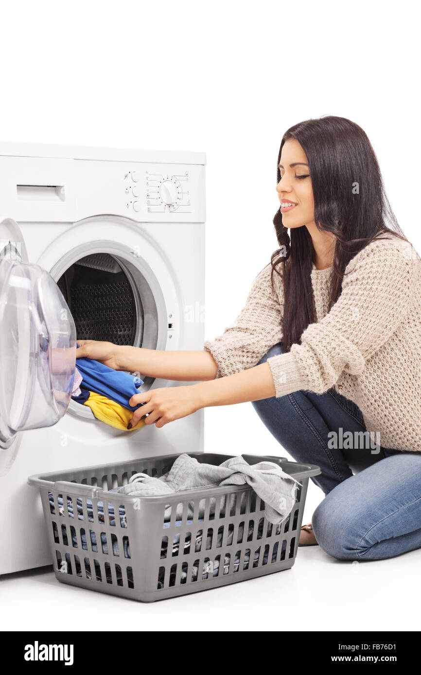 Vertical shot of a young woman emptying a washing machine isolated on white background Stock Photo