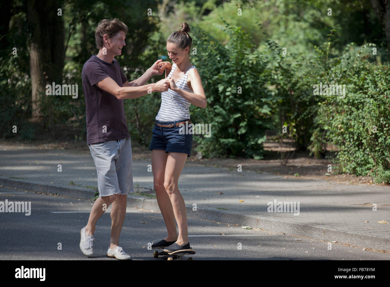 Young man teaching woman to skating Stock Photo