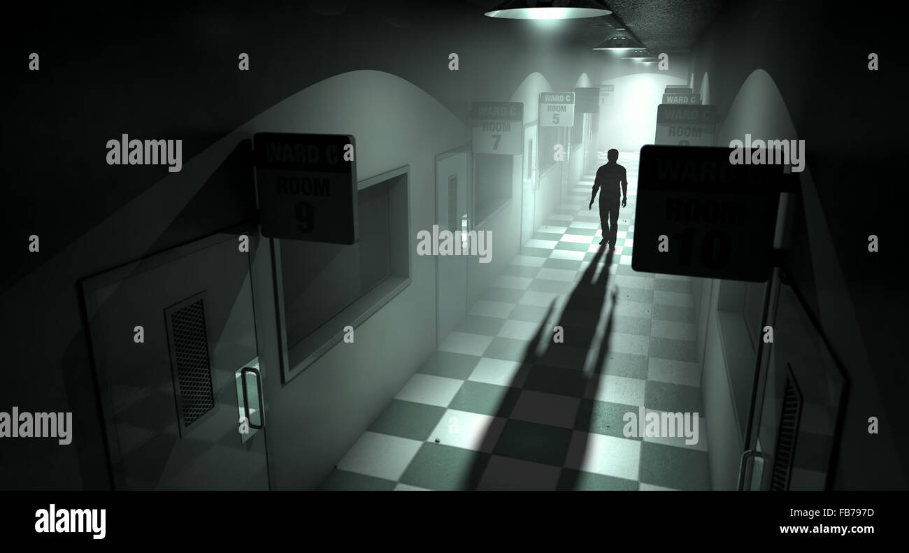 A ghostly figure casts a long shadow down the middle of a dimly lit passage of a dilapidated mental asylum Stock Photo