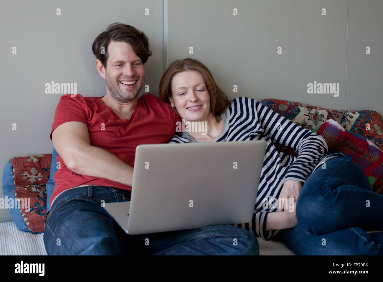 Couple using laptop while lying on sofa Stock Photo