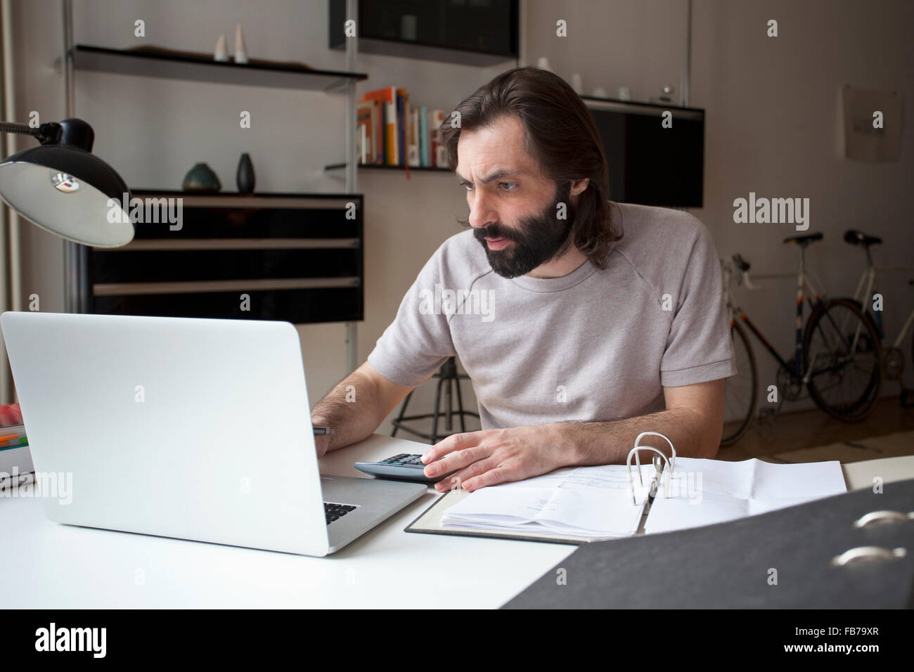 Mid adult man working on laptop at home Stock Photo