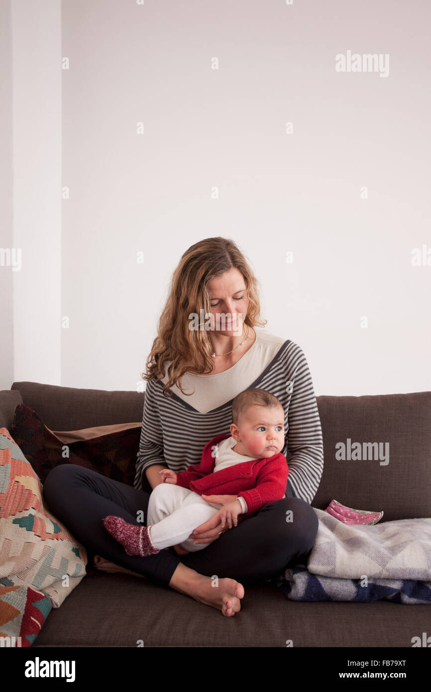 Woman sitting with baby girl on sofa at home Stock Photo