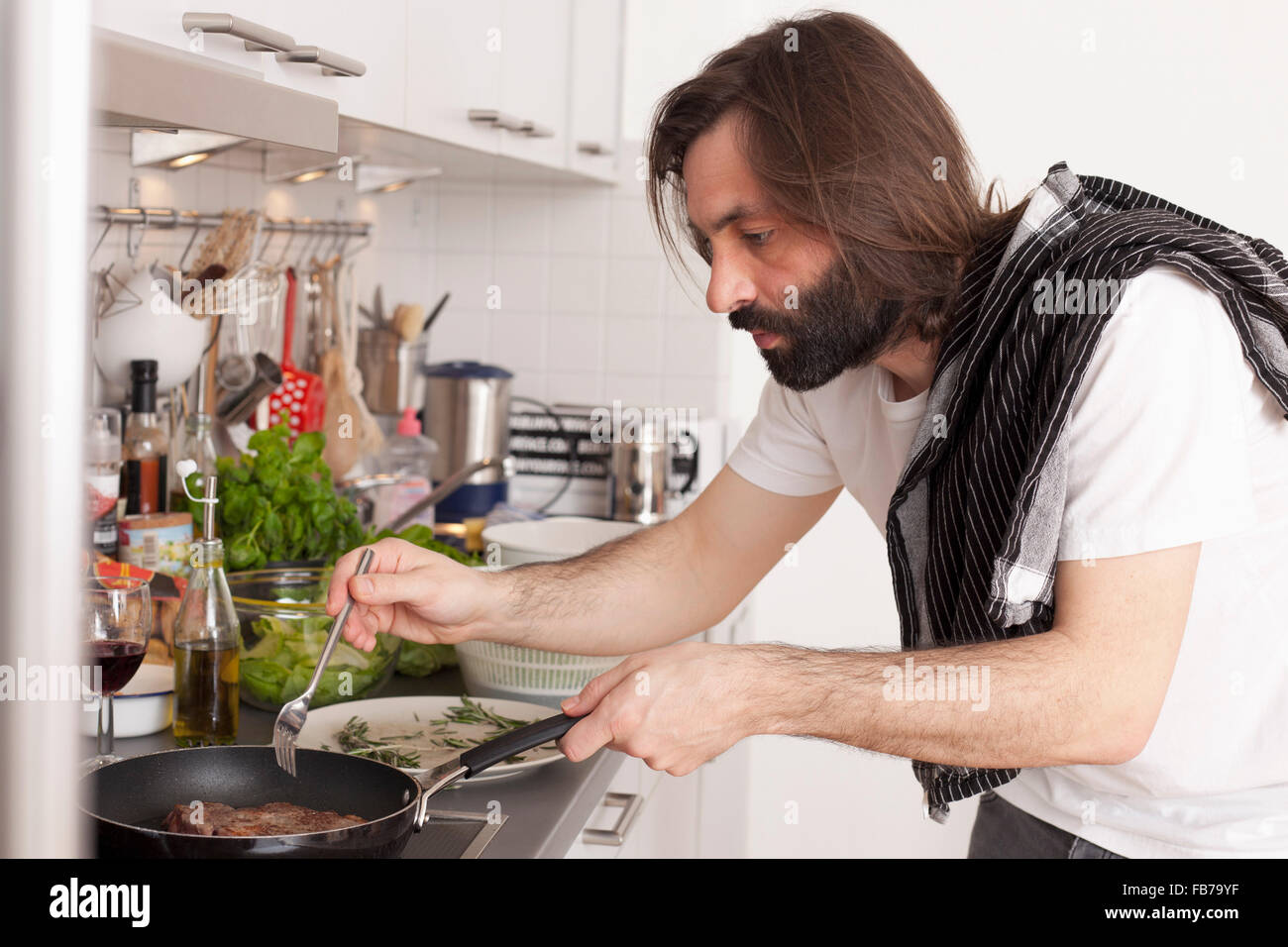 Mid adult man preparing meat in domestic kitchen Stock Photo