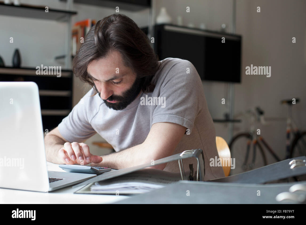 Mid adult man using calculator at table Stock Photo