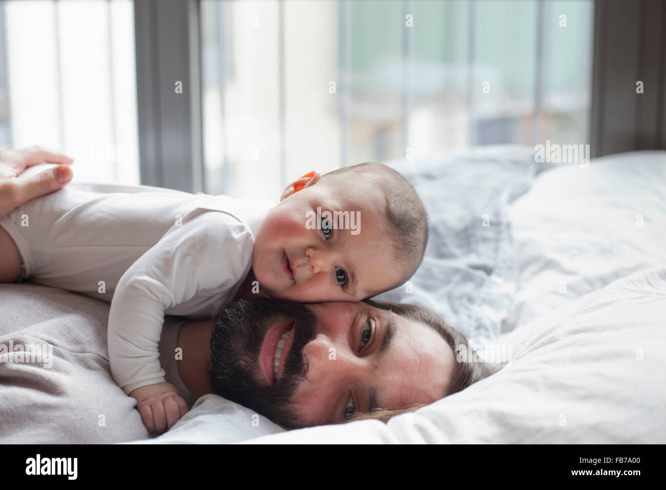 Portrait of loving father with baby girl lying in bed Stock Photo
