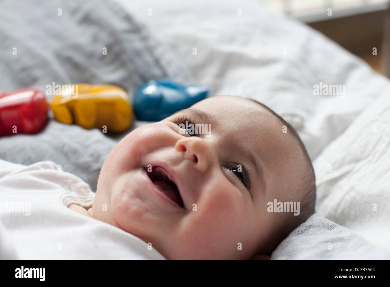 Close-up of cheerful baby girl lying in bed Stock Photo