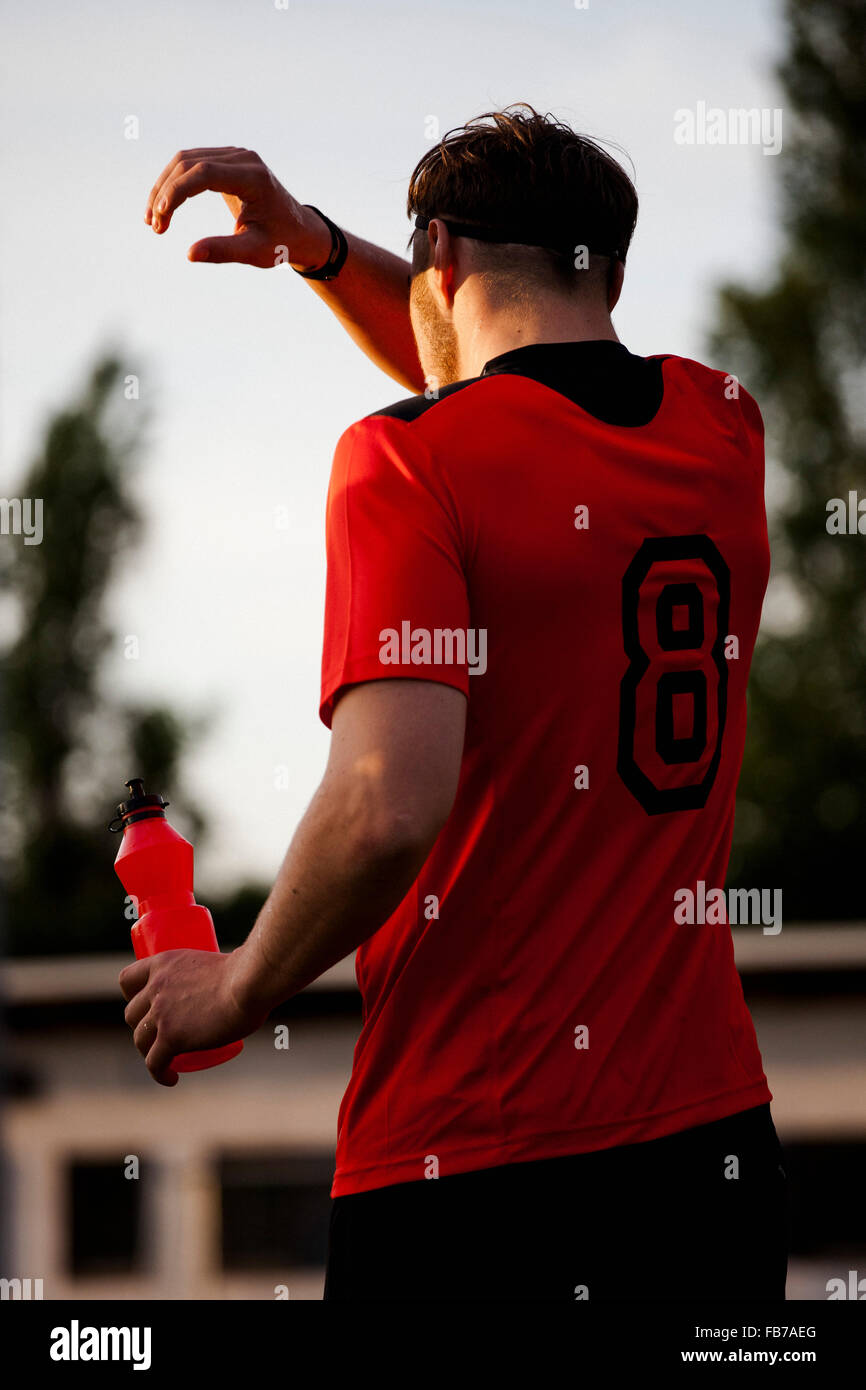 Rear view of tired sportsman cleaning sweat on face Stock Photo