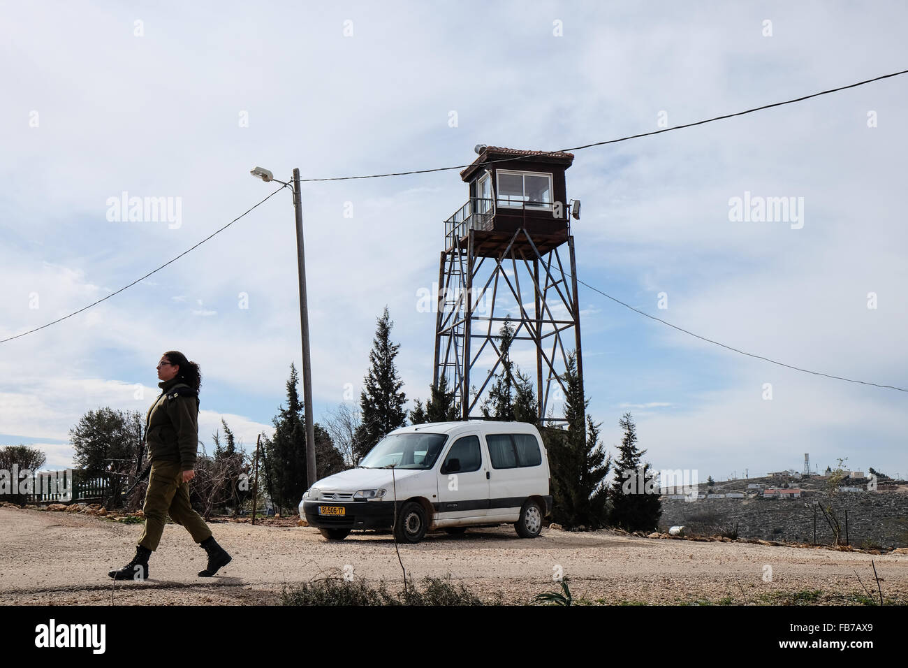 Esh Kodesh, West Bank. 11th January, 2016. An IDF officer walks past the guard tower in the Esh Kodesh Israeli outpost in the West Bank near Shilo, under the jurisdiction of the Mateh Binyamin Regional Council. The guard tower manned by IDF soldiers is visible in the background. The settlement was established in 1999 and is now home to some 40 families who consider it an unauthorized community of Shilo in the process of becoming formally authorized. Stock Photo