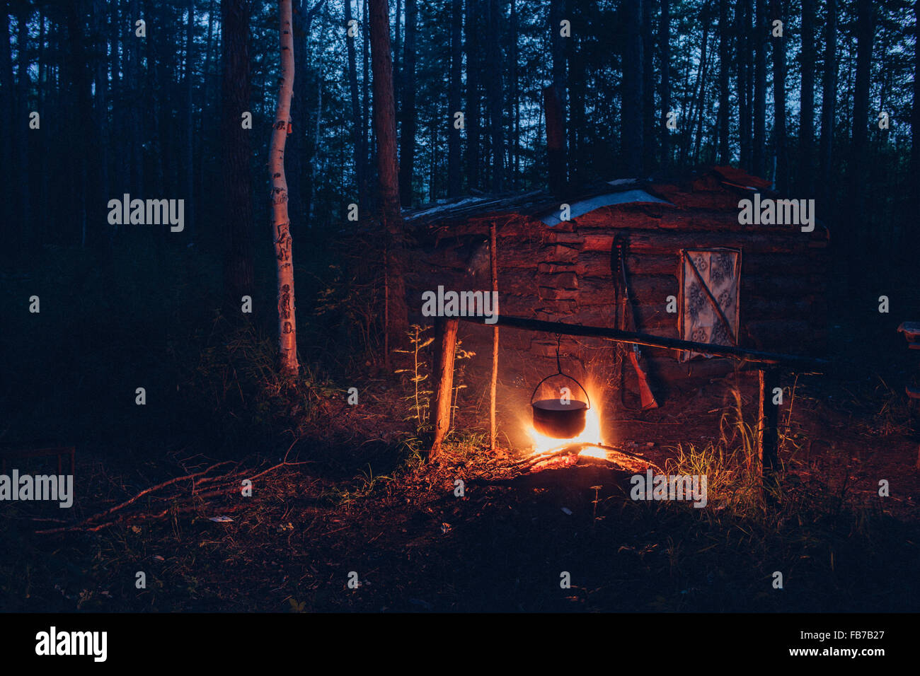 Container hanging over campfire in forest Stock Photo