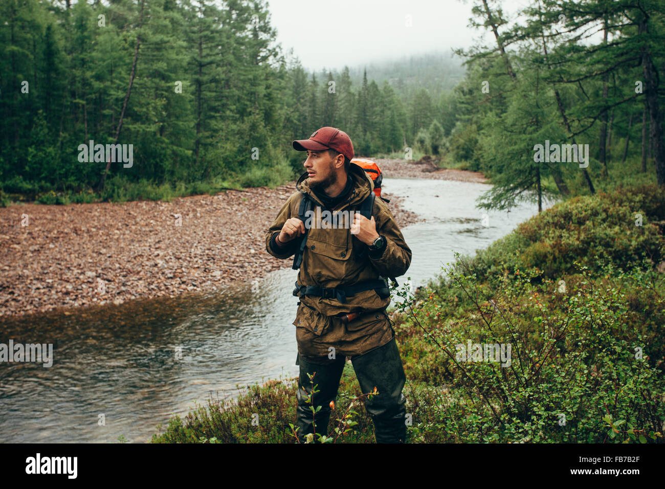 Mid adult man standing by river in forest Stock Photo