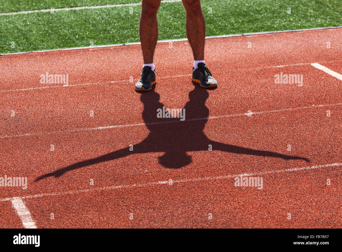 Low section of young male athlete exercising on race track Stock Photo