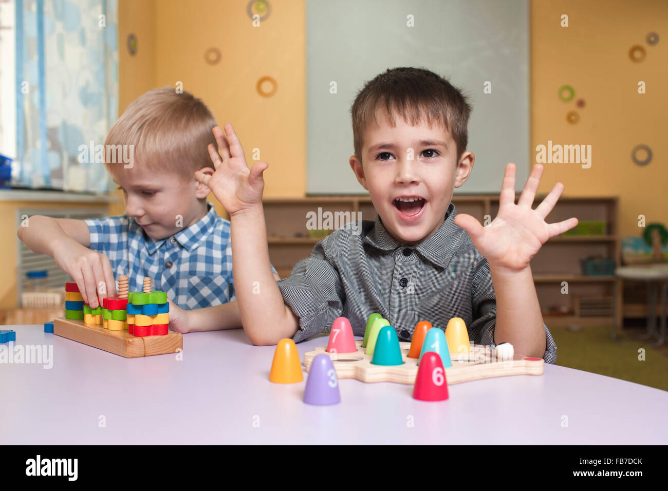 Cute little boys playing with toys at table in classroom Stock Photo