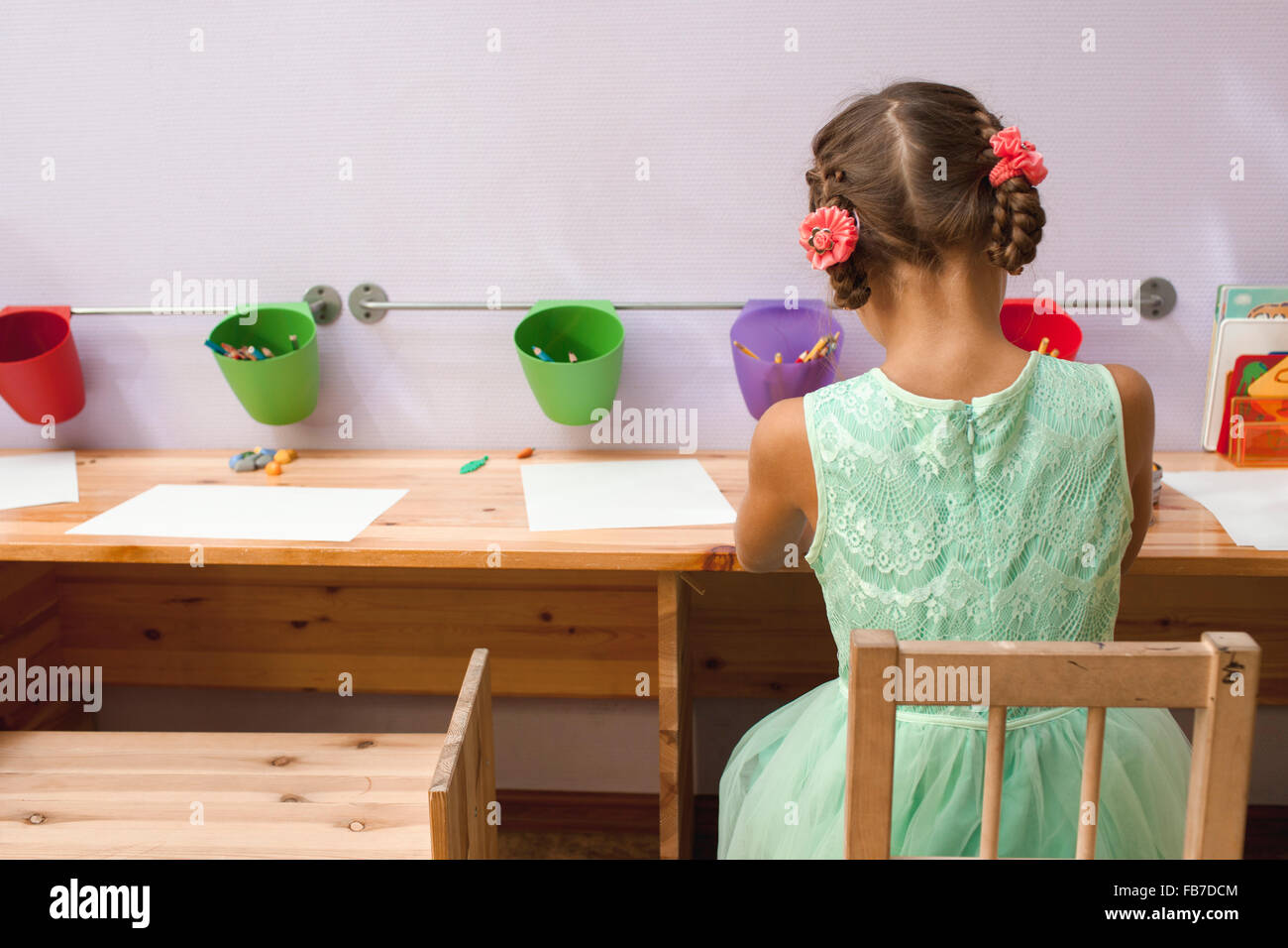 Rear view of girl drawing at desk in classroom Stock Photo