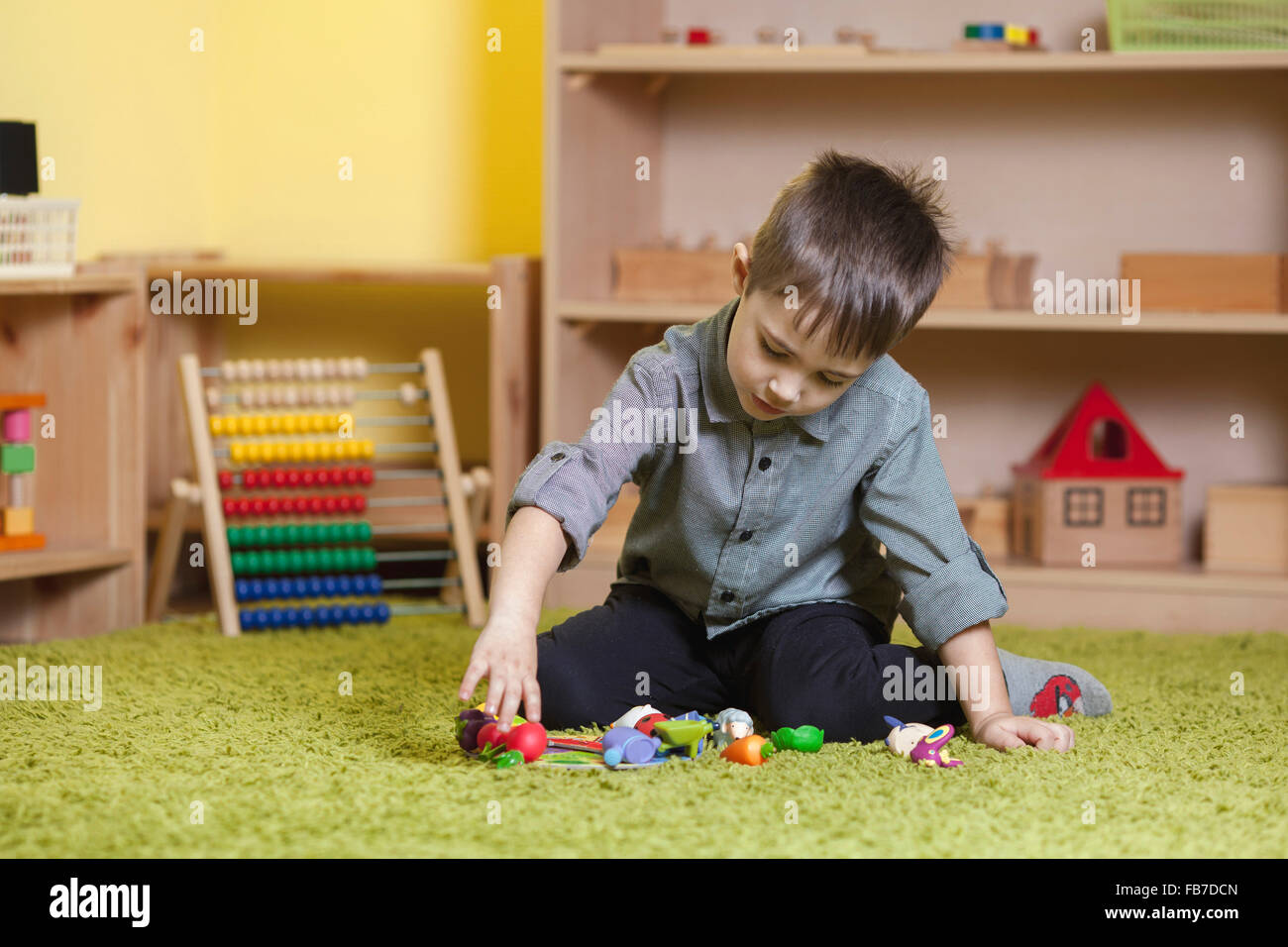 Full length of boy playing with toys on rug in classroom Stock Photo
