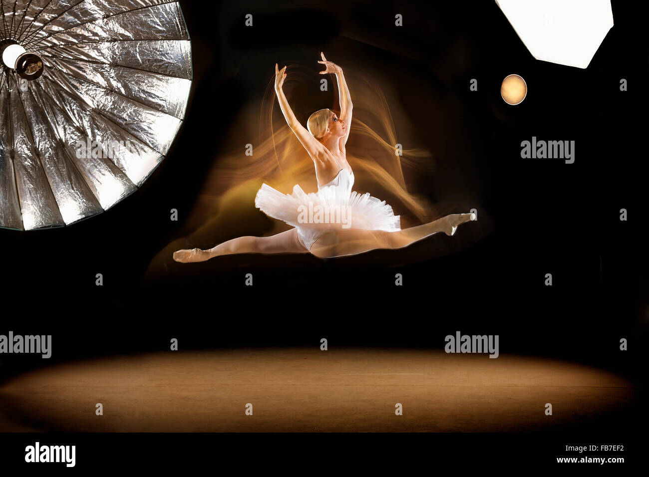 Full length of ballerina doing splits in mid-air at studio Stock Photo