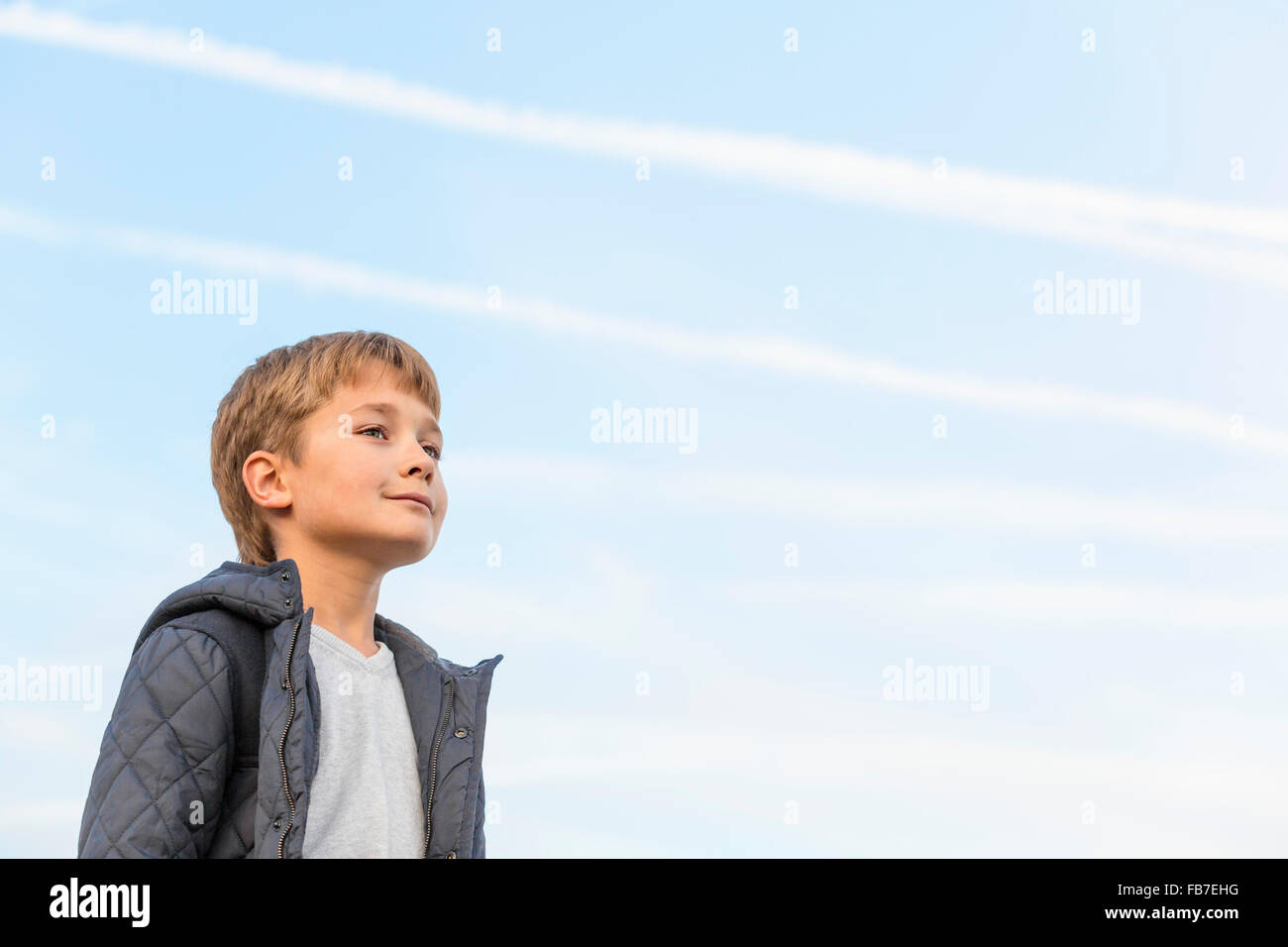 Low angle view of boy looking away against sky Stock Photo