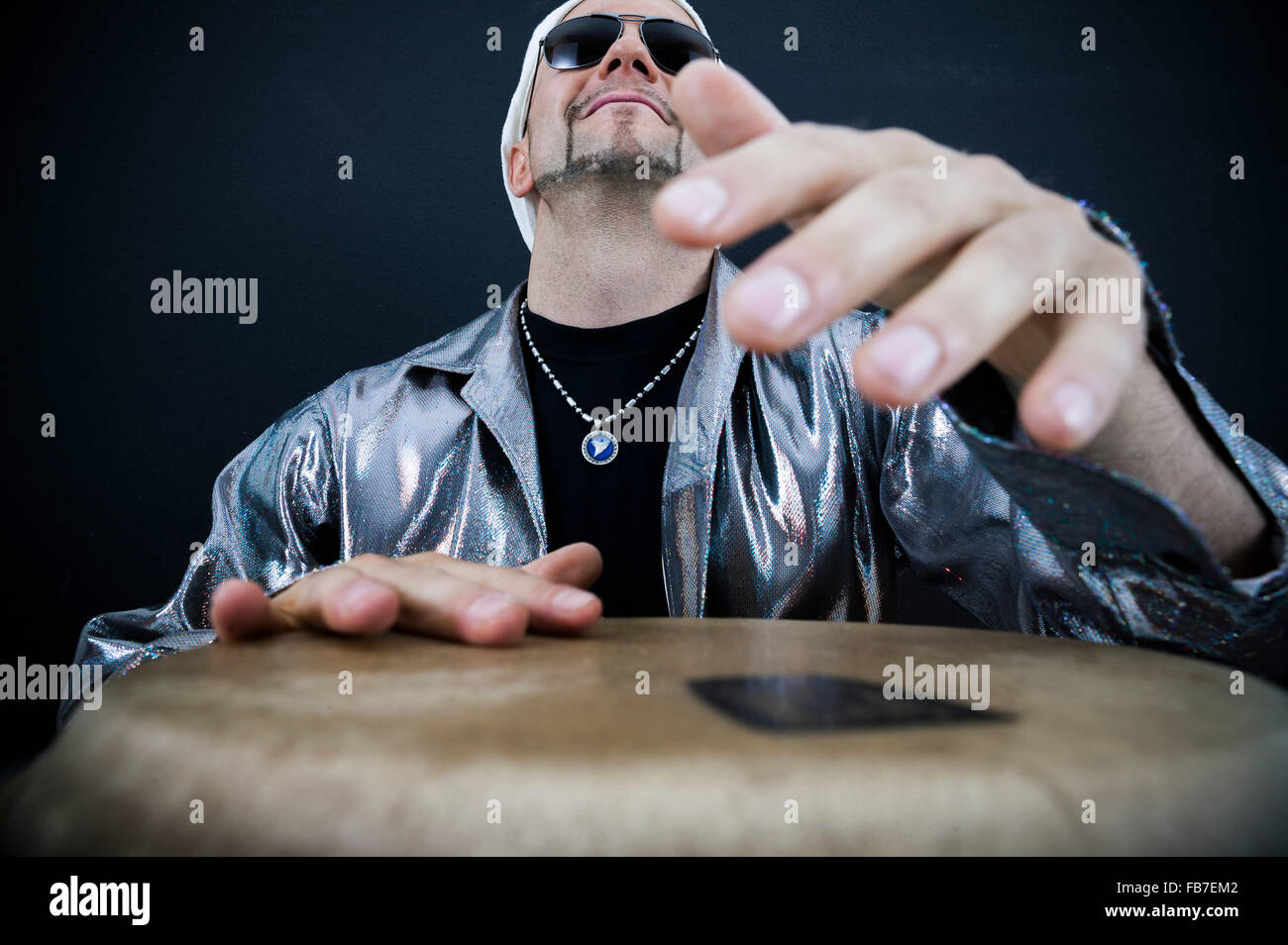 Mature man playing drum against black background Stock Photo