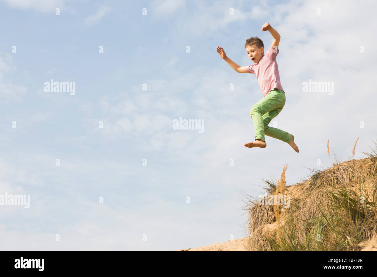 Low angle view of boy jumping against sky Stock Photo
