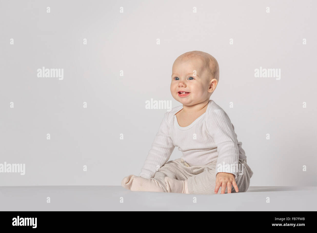 Happy baby girl sitting against white background Stock Photo