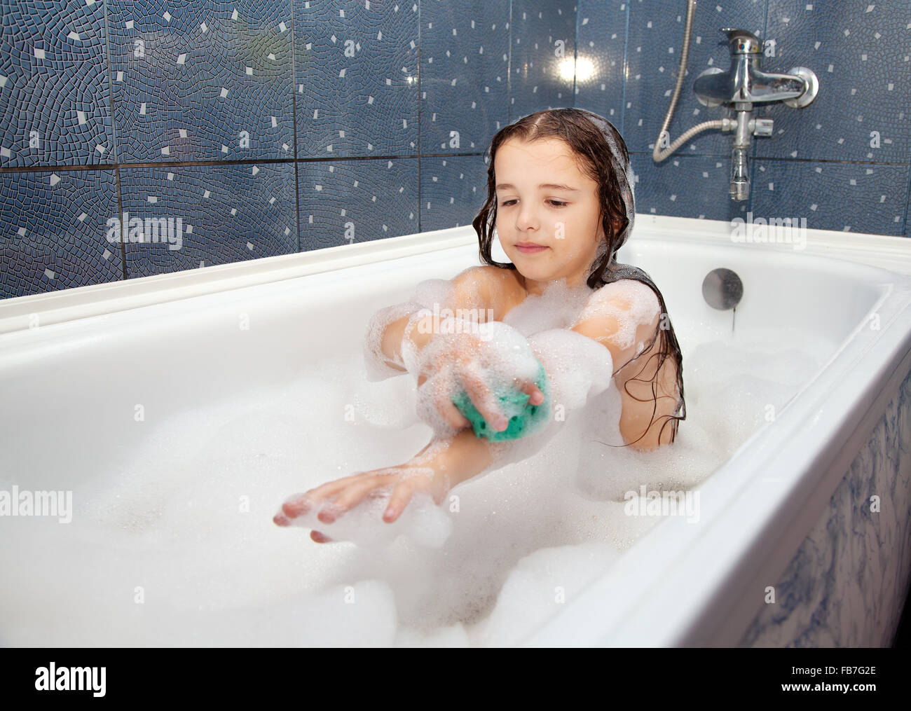 little girl washing her hand with sponge sitting in the bath closeup ...