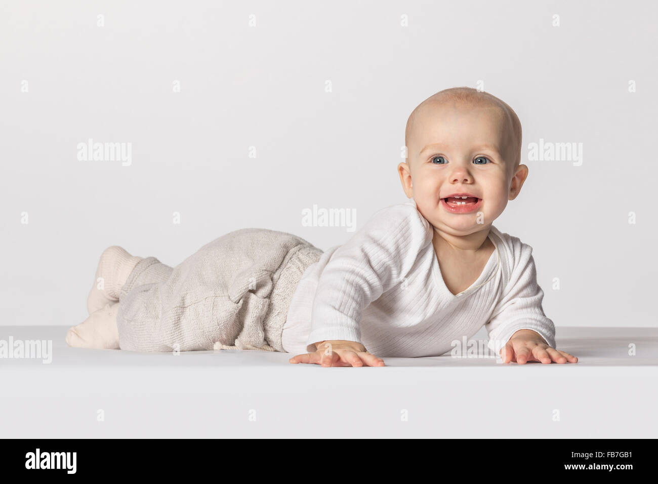 Happy baby girl lying against white background Stock Photo