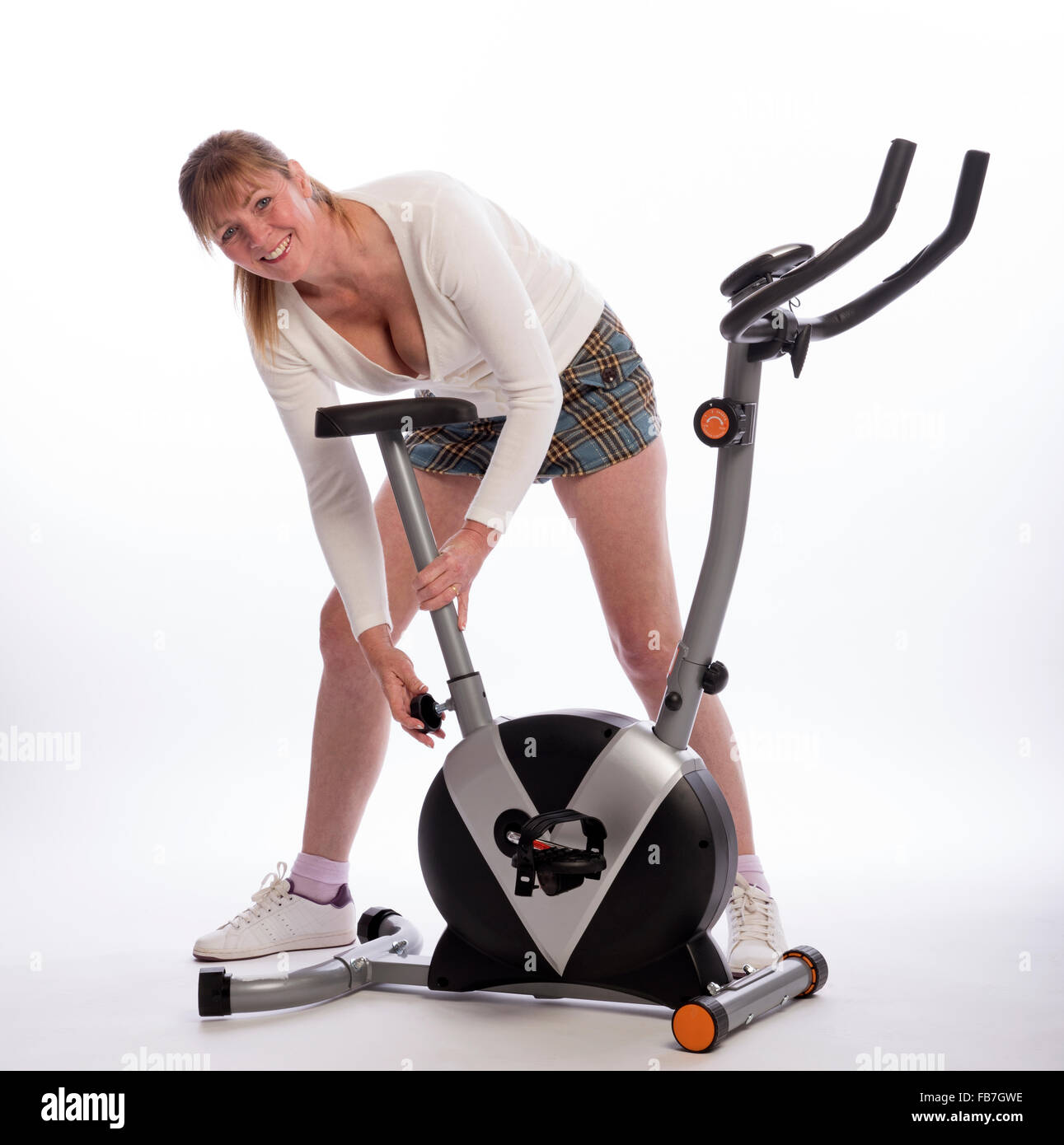 Woman adjusting the height of the saddle on an exercise bike Stock