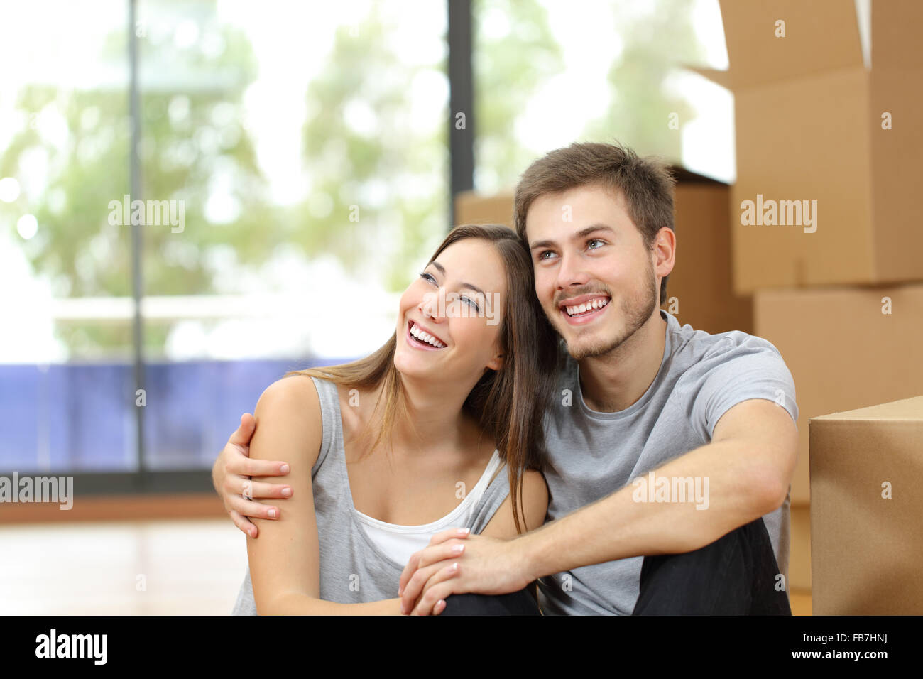 Happy couple moving home planning and looking sideways Stock Photo