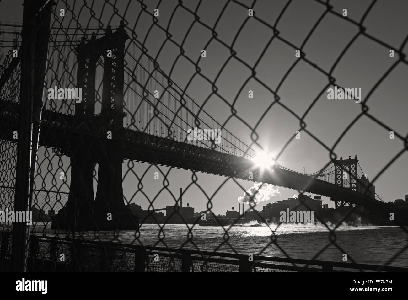 Distorted industrial view of Manhattan Bridge waterfront New York City through a wire safety fence. Monochrome, black and white image. Stock Photo