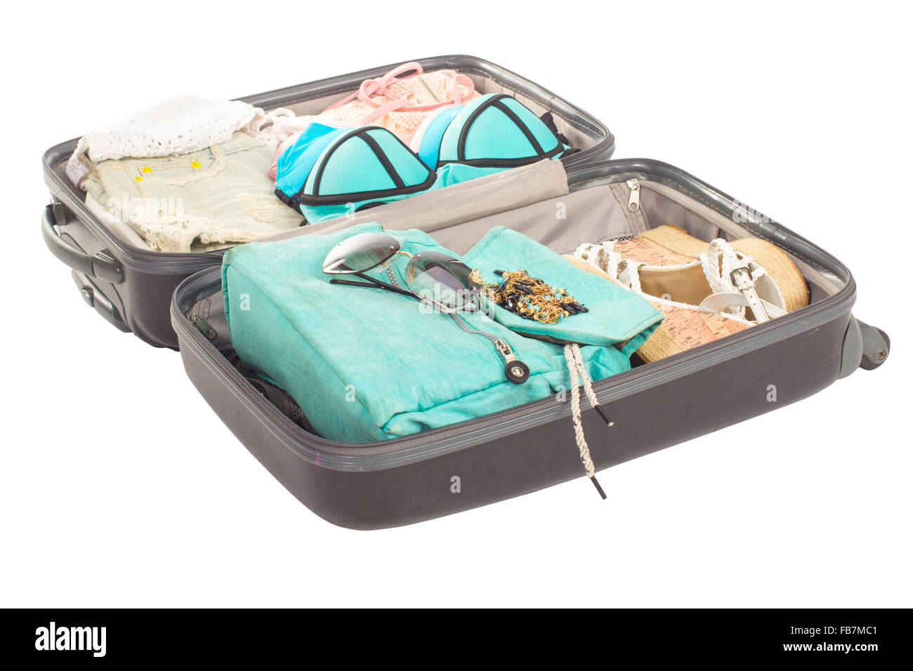 Packed, opened suitcase full of vacation items. Stock Photo