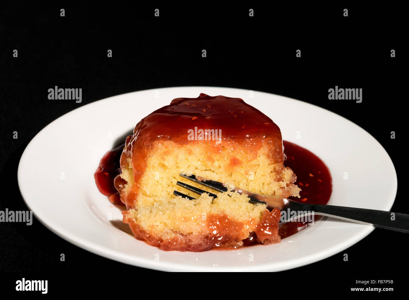 Jam sponge pudding - studio shot with a black background Stock Photo