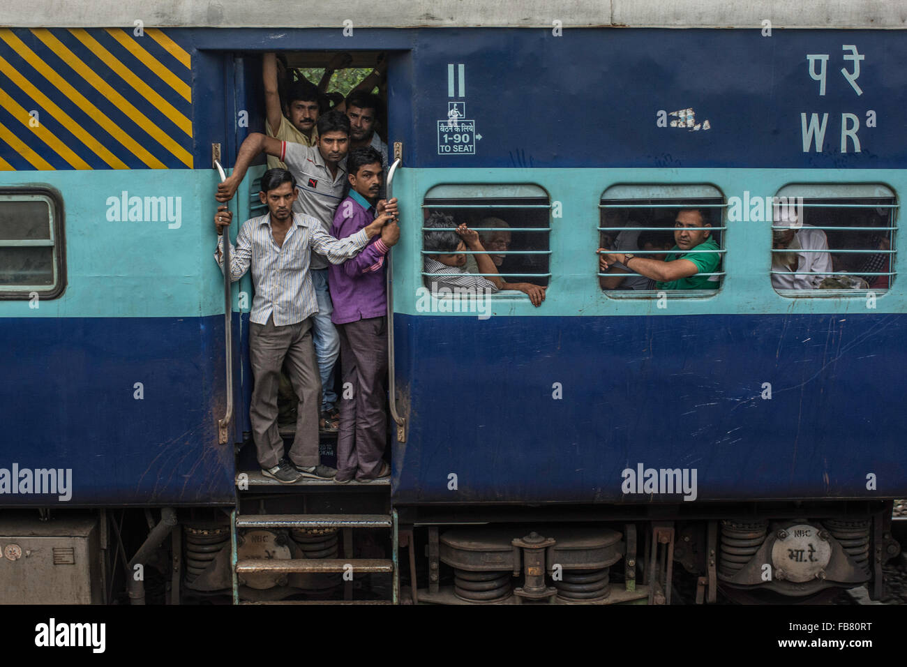 Passengers looking out of crowded train. Indian Railways, Rajasthan, India. Stock Photo