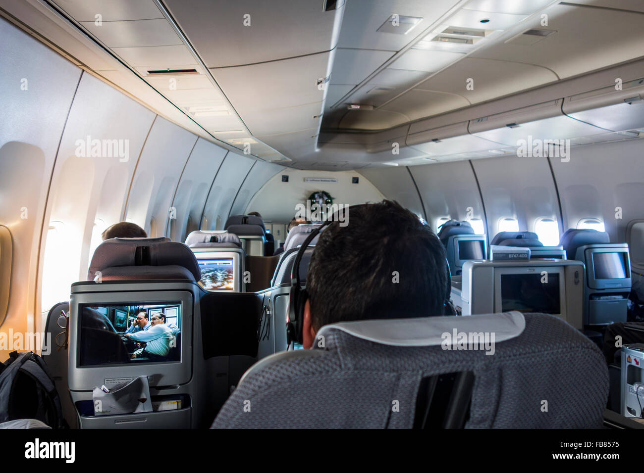 passengers in business class cabin watching entertainment screens, Lufthansa 747 plane in flight Stock Photo
