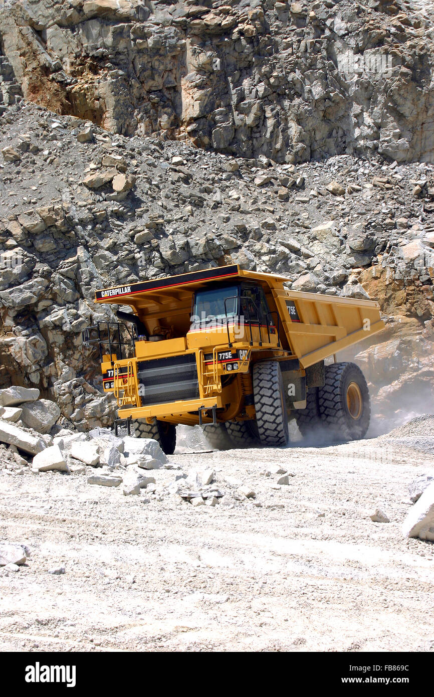 A huge dump truck loaded with blasted rock begins its long journey to