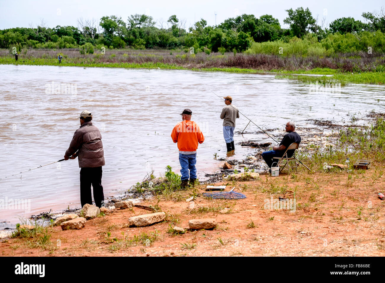 People fish in the rising waters of Hefner Lake in Oklahoma City after a spring rain. Oklahoma, USA. Stock Photo