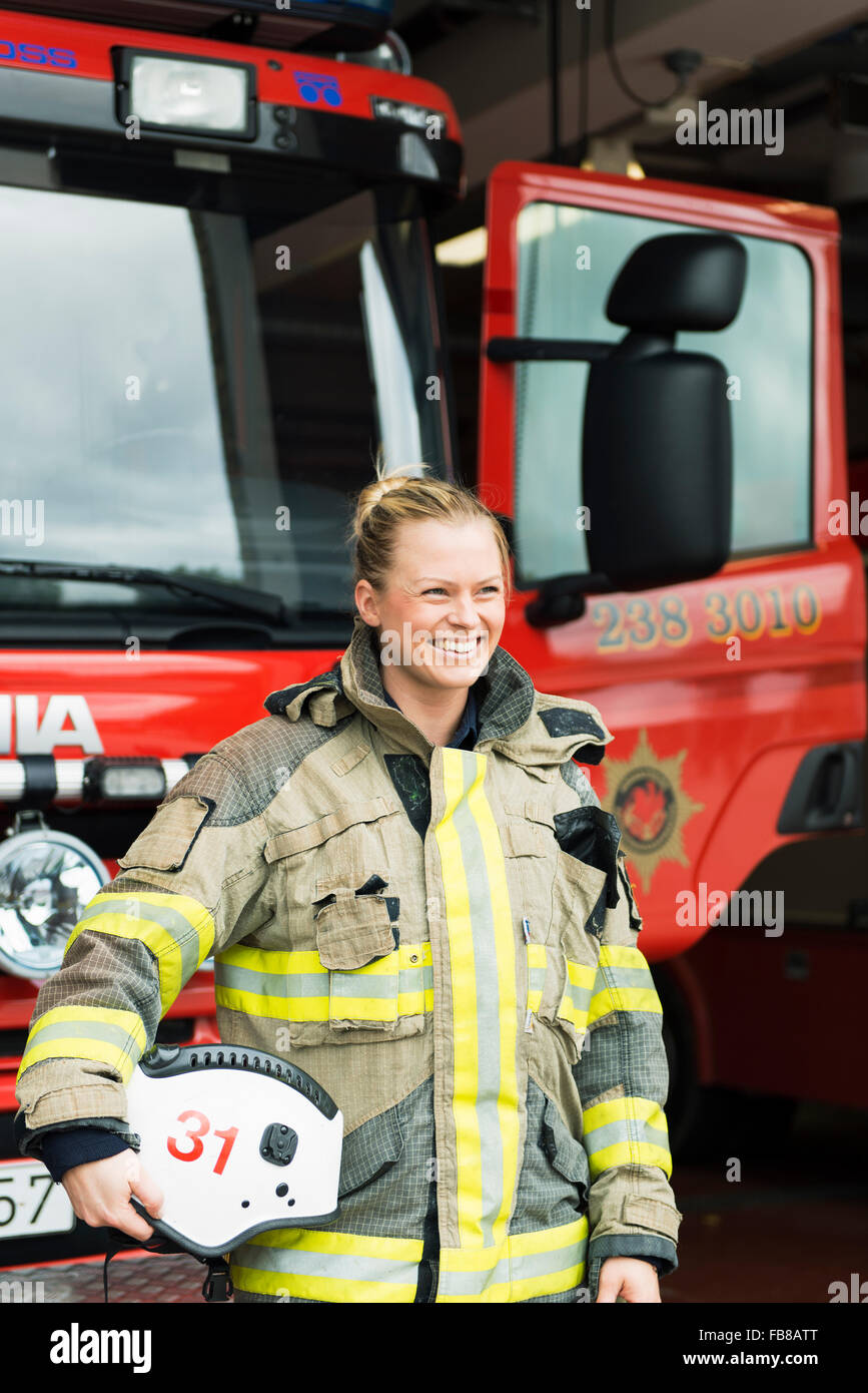 Sweden, Smiling female firefighter by fire engine Stock Photo