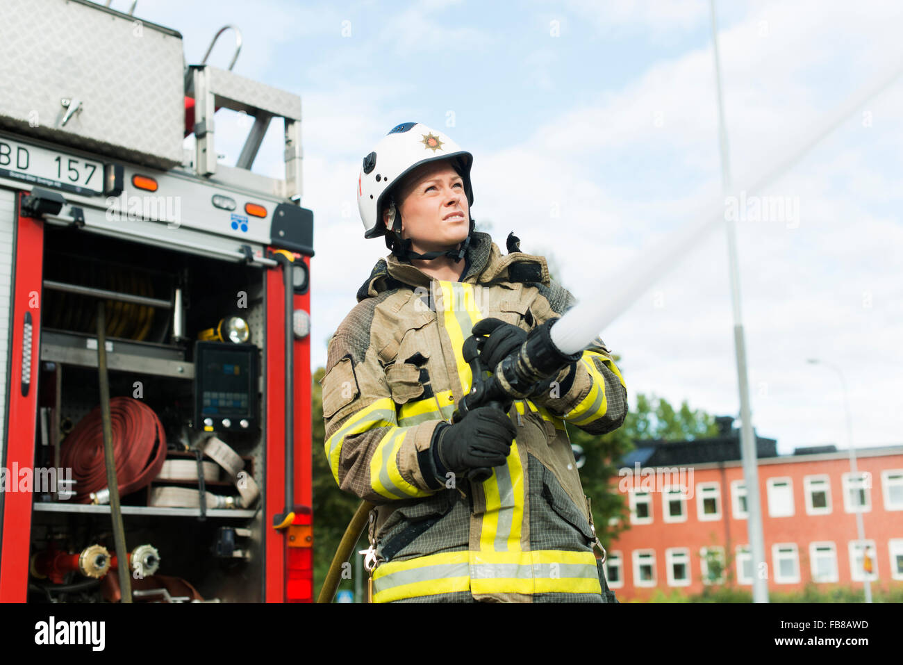 Sweden, Sodermanland, Sodertalje, Female firefighter using fire hose next  to truck Stock Photo - Alamy