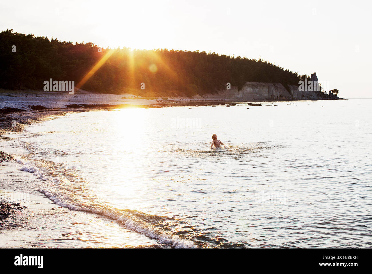 Sweden, Gotland, Lickershamn, Boy (8-9) swimming in ocean at sunset Stock Photo